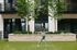 Elegant apartment courtyard featuring lush greenery and a woman practicing yoga, highlighting a serene urban oasis.
