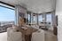 Modern living and dining area with panoramic city views, featuring elegant furniture, large windows, and a cozy seating arrangement.