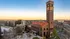 Stunning view of a historic brick tower and modern apartment buildings at sunset.