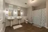 Spacious modern bathroom with dual sinks, elegant lighting, and stylish patterned shower curtain.