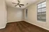 Spacious room with plush brown carpet, elegant ceiling fan, and large windows for natural light.