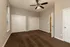 Spacious bedroom with elegant sliding closet doors, plush carpeting, and a modern ceiling fan in a chic apartment.