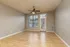 Spacious and bright living area with sleek wooden flooring and large windows inviting natural light, complemented by a modern ceiling fan.