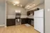 Modern kitchen with stainless steel appliances, sleek dark cabinets, and bright track lighting on polished wood floors.