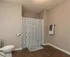 Spacious and modern bathroom with elegant tiled flooring, featuring a stylish shower curtain and neatly arranged towels.