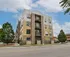 Modern urban apartment building with stylish architecture, large windows, and lush greenery in a vibrant neighborhood.