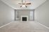 Cozy living room with plush carpet, elegant ceiling fan, and a classic fireplace, offering a serene ambiance at Driscoll Place.