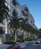 Modern luxury apartment building with elegant balconies and palm-lined street, showcasing sophisticated urban living.