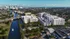 Stunning aerial view of modern apartment complex beside a serene canal in a vibrant cityscape, offering urban luxury and waterfront tranquility.