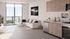 Bright and modern living space with sleek kitchen, cozy white sofa, and floor-to-ceiling windows offering stunning views.