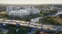Elegant riverside apartment complex with modern architecture, lush greenery, and convenient location near a major highway, offering serene urban living.