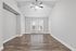 Bright and spacious living area with elegant wooden flooring, modern ceiling fan, and double doors leading to a balcony.