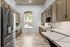 Luxurious modern kitchen with sleek stainless steel appliances, elegant marble flooring, and custom cabinetry, boasting abundant natural light.
