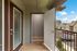 Inviting balcony entrance with a wooden deck, offering a charming view of the serene neighborhood and clear blue skies.