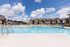 Inviting sunny apartment complex with a large sparkling pool, surrounded by comfortable lounge chairs and framed by a beautiful blue sky.