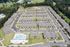 Scenic aerial view of a sprawling apartment community with neatly arranged buildings, ample parking, and lush green surroundings, featuring a luxurious pool area for residents.