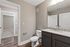 Modern bathroom with elegant granite countertop, sleek fixtures, and a view into a cozy, carpeted bedroom.