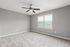 Bright and airy bedroom room with plush carpet, large window, and modern ceiling fan.