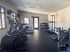 Modern apartment gym with top-tier fitness equipment, including treadmills and weights, bathed in natural light.