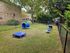 Charming fenced dog park with agility equipment, nestled in a green, peaceful residential area.