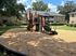 Charming apartment community playground with vibrant play equipment, surrounded by lush greenery and cozy brick buildings.