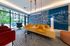 Modern lounge area with vibrant decor, featuring comfy seating, a sleek map wall mural, and large windows overlooking our stylish outdoor space.