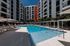 Luxurious apartment complex with modern pool area, stylish lounge chairs, and sleek architecture in a vibrant setting.