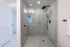 Luxurious spa-inspired shower with sleek glass doors and elegant fixtures in a serene tile setting.