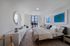 Elegant spacious bedroom featuring recessed lighting, stylish architectural design, beautiful porcelain floors and expansive window for natural light.