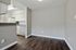 Modern apartment kitchen with sleek white cabinets, granite countertops, and rich wooden flooring, offering a clean and inviting space.