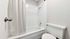 Minimalist bathroom featuring a white bathtub, shower, and modern fixtures.