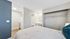 Modern bedroom with a large open closet, ensuite bathroom, and adjacent kitchenette.