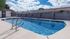 Inviting outdoor pool with clear blue water, surrounded by a sunlit deck and privacy fencing.