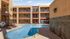 Modern apartment complex featuring a central swimming pool surrounded by a sunlit courtyard.