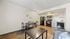 Modern apartment living room with a cozy dining area and sleek kitchen featuring black appliances.