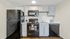 Modern kitchen with black appliances, white cabinets, and wood flooring.