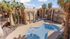 Luxury apartment complex with a serene pool area surrounded by palm trees and three-story buildings.