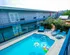 Vibrant outdoor pool surrounded by modern two-story apartment complex with lounge chairs and colorful pool floats.