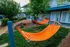Inviting outdoor area with vibrant orange hammocks in a landscaped garden setting.