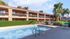 Inviting apartment complex with a sparkling outdoor pool, surrounded by lush greenery and charming two-story buildings.