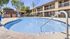 Inviting outdoor swimming pool surrounded by lush greenery and modern apartment buildings, perfect for relaxation and leisure.