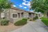 Charming leasing office with welcoming pathway, set amidst beautifully landscaped greenery and bright blue skies.