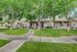 Charming apartment building with red doors, nestled among lush green trees and well-maintained lawns.