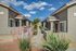 Charming modern apartment complex with beautifully manicured landscaping and vibrant flora under a clear blue sky.