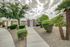 Inviting apartment entrance with lush landscaping, featuring palm trees and manicured shrubs under a vibrant sky.