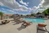 Inviting outdoor pool area with stylish loungers and a picnic table under a bright blue sky with fluffy clouds.