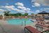 Inviting outdoor pool area with comfortable lounge chairs and umbrellas, perfect for relaxation under a bright, blue sky.