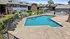 Inviting apartment complex with a pristine swimming pool, surrounded by comfortable lounge chairs and lush landscaping.