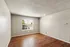 Bright and airy room with rustic wooden flooring, large window providing ample natural light, ideal for a cozy living area.