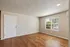 Inviting living space featuring gleaming wooden floors, a large window for natural light, and a neutral color palette.